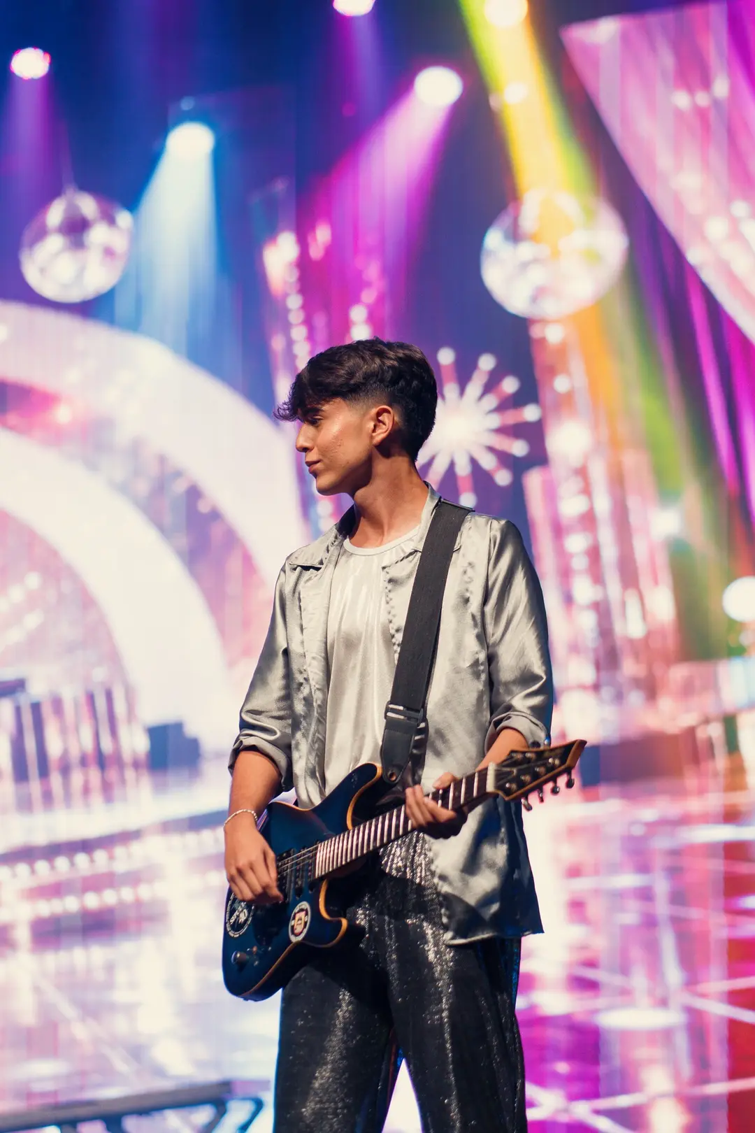 Aluno guitarrista diante de um telão pink