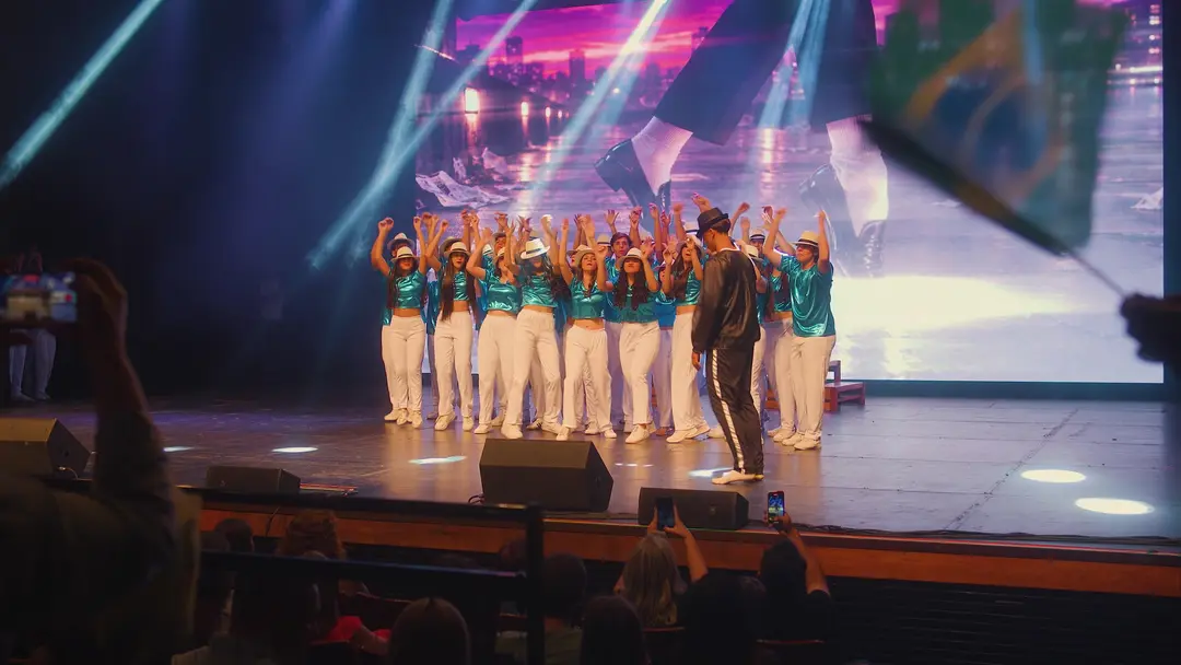Elenco em coreografia de chapéus sob as luzes do Fest Show